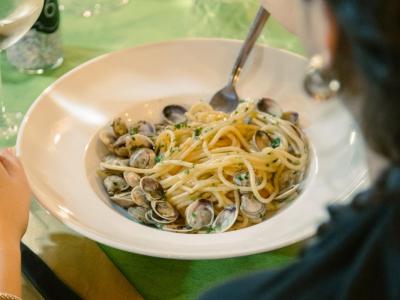 Plate of spaghetti with clams on a set table.