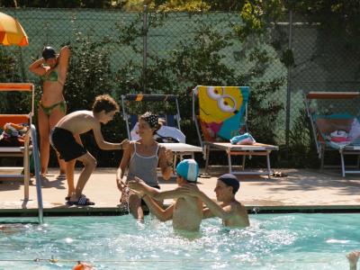 Persone si divertono in piscina sotto il sole estivo.