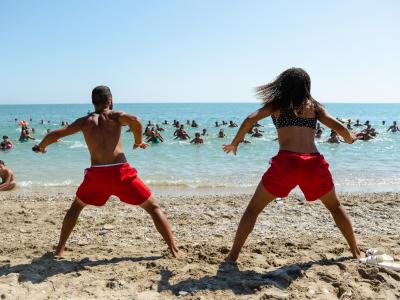 Persone fanno ginnastica sulla spiaggia, vista mare.