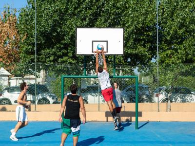 Four boys playing basketball outdoors.