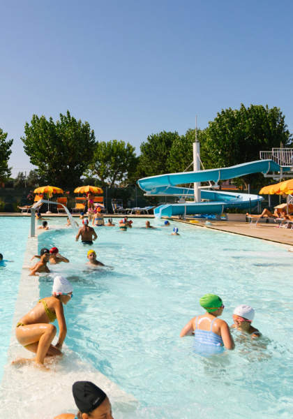 Piscina all'aperto con scivolo e ombrelloni gialli.