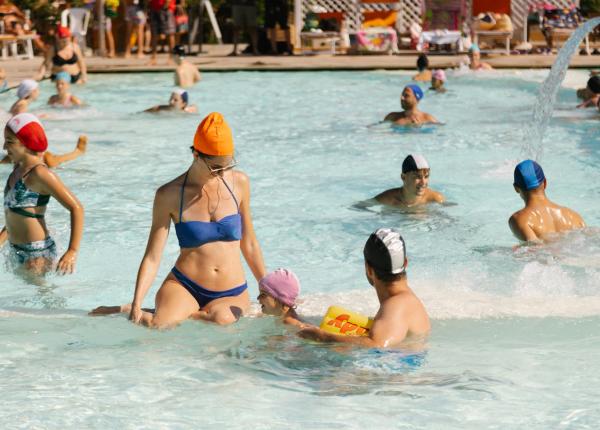 Persone si divertono in piscina con cuffie colorate.