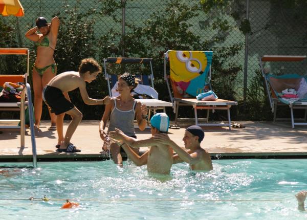 Persone si divertono in piscina sotto il sole estivo.