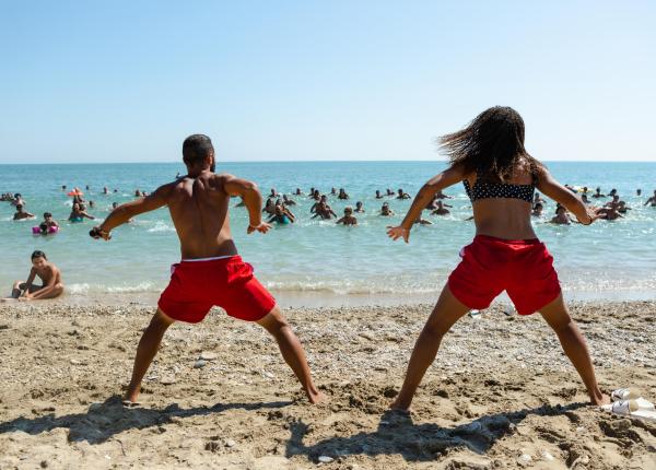 Persone fanno ginnastica sulla spiaggia, vista mare.