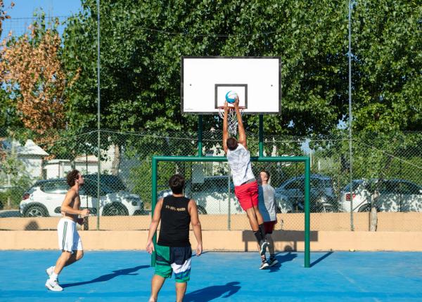 Four boys playing basketball outdoors.